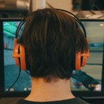 Guy with headphones sitting in front a computer screen playing game