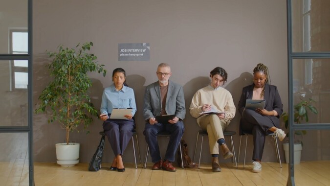 A diverse group of candidates waiting for a job interview in an office hallway