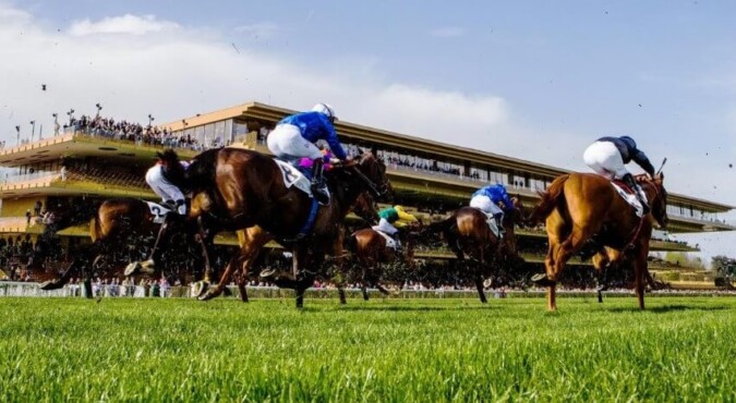Horse race with jockeys in colorful silks thundering down the track towards a grandstand