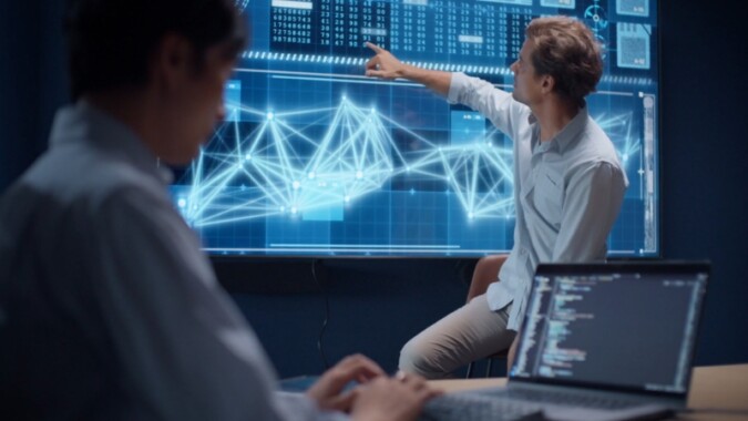Two engineers review data and network models on a large digital screen in an advanced engineering workspace