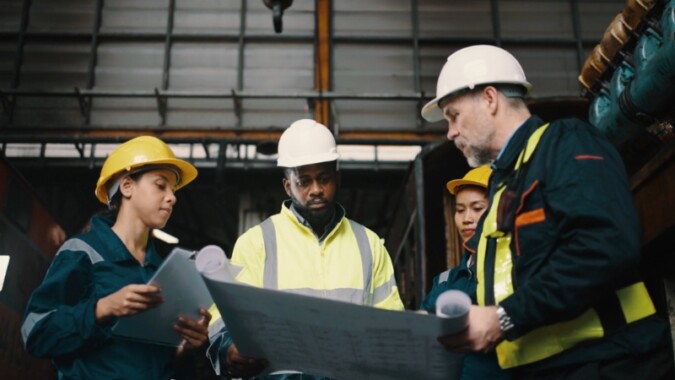 Engineers in hard hats review site plans together on an industrial project