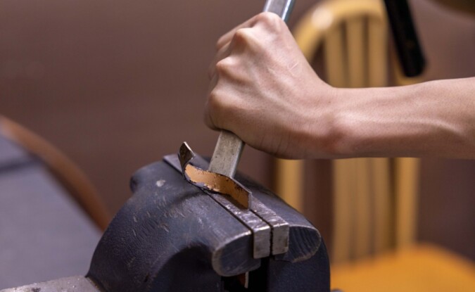 Craftsperson shaping metal by hand with a hammer and chisel in a workshop