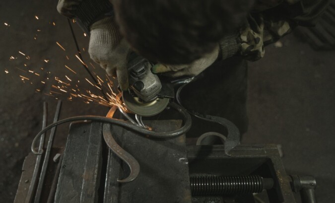 Metalworker grinding a fabricated part and sending sparks across a workshop